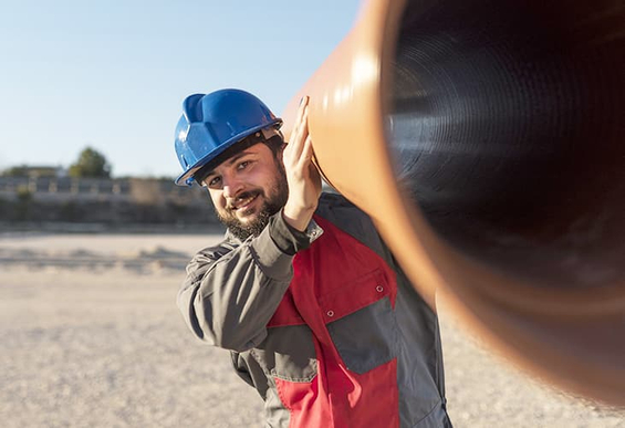 Rohrleitungsbauer der ein Abwasserrohr trägt